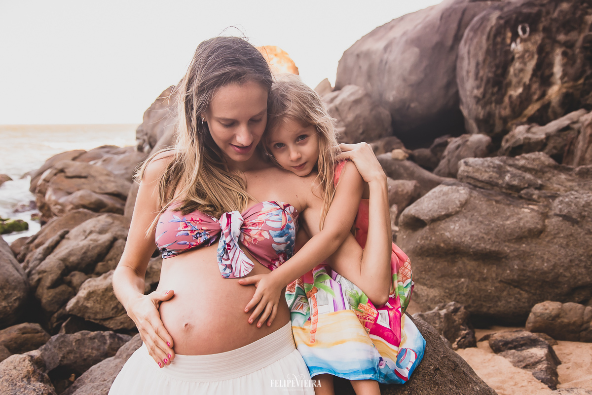 mãe e filha se abraçando gestante de cropped colorido estampado inspiração ensaio de familia na praia dos padres em Guarapari