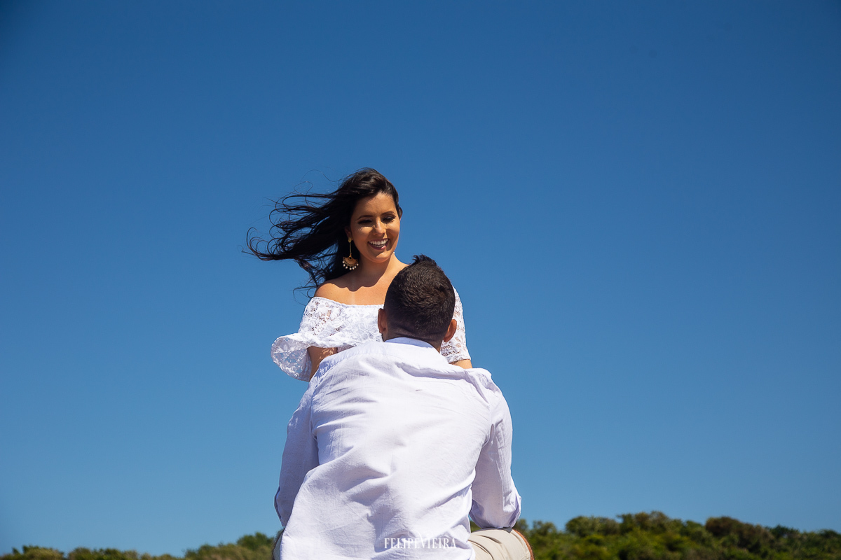 noiva sorrindo para noivo look branco céu azul ensaio pré wedding Guarapari
