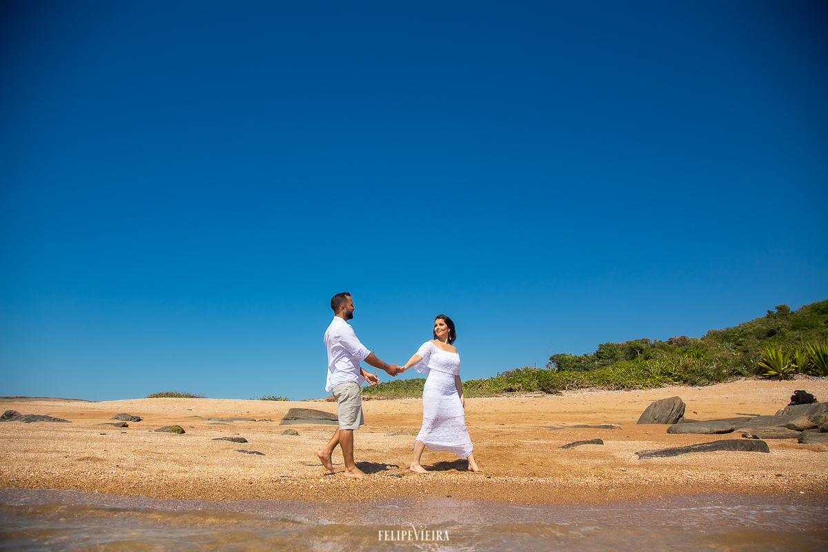 noiva de Guarapari andando com o noivo na areia branca da praia 