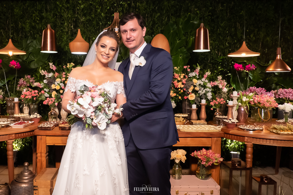 casal de noivos na frente de mesa do bolo em casamento em Alfredo Chaves