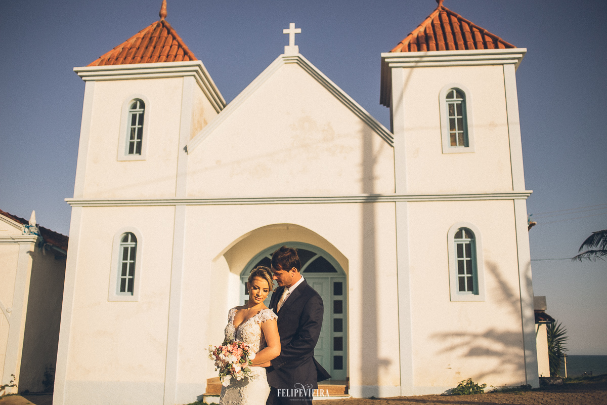 noivo abraçando a noiva em ensaio fotográfico na frente da igreja em Meaípe Guarapari ES