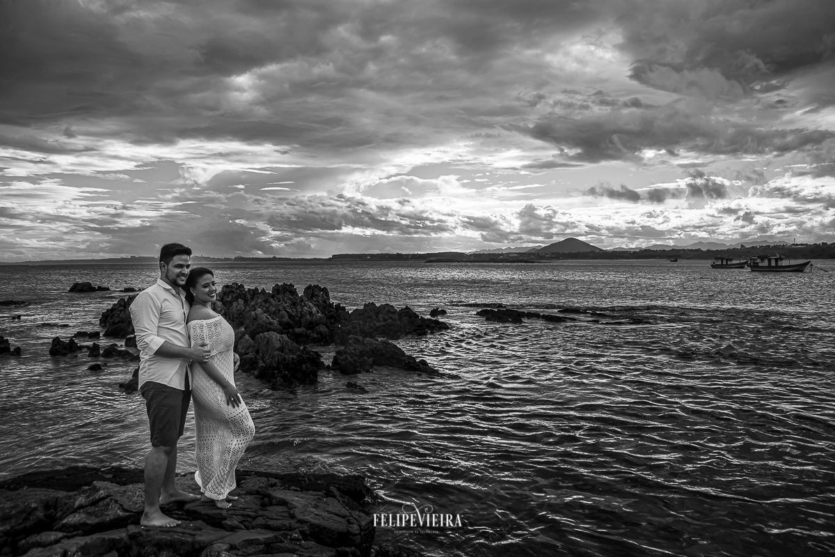fim de tarde nublada em Guarapari com noivos sobre pedras da praia foto em preto e branco noivos de branco