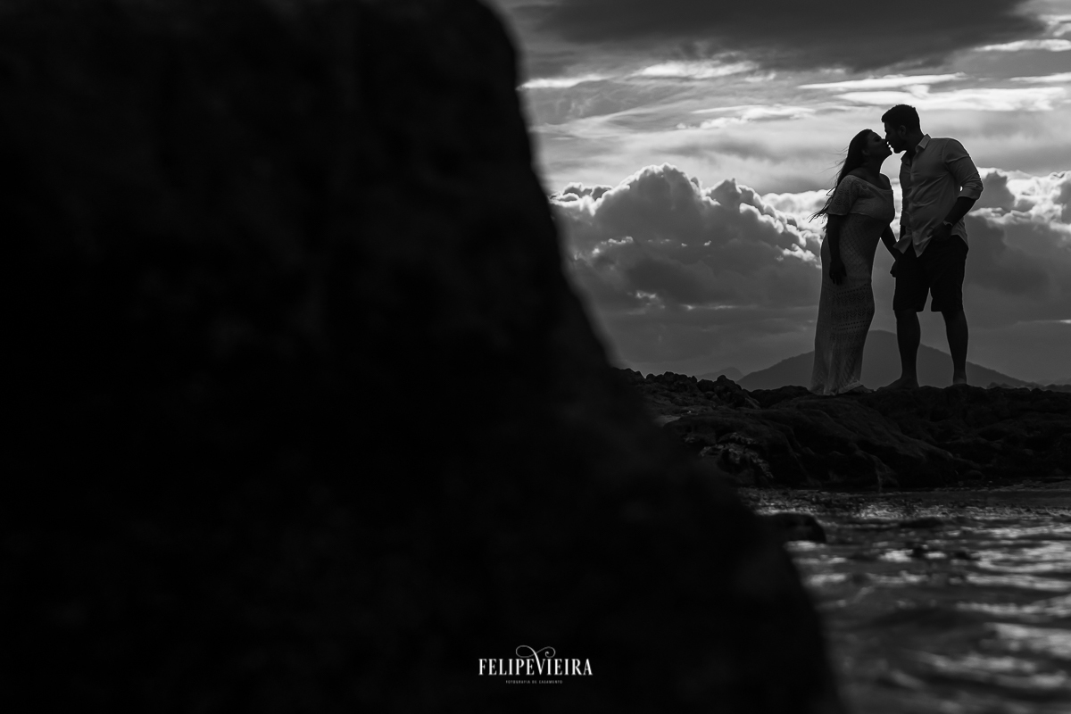 fim de tarde na praia de Meaípe Guarapari com os noivos em silhueta em foto preto e branco com o noivo beijando a noiva