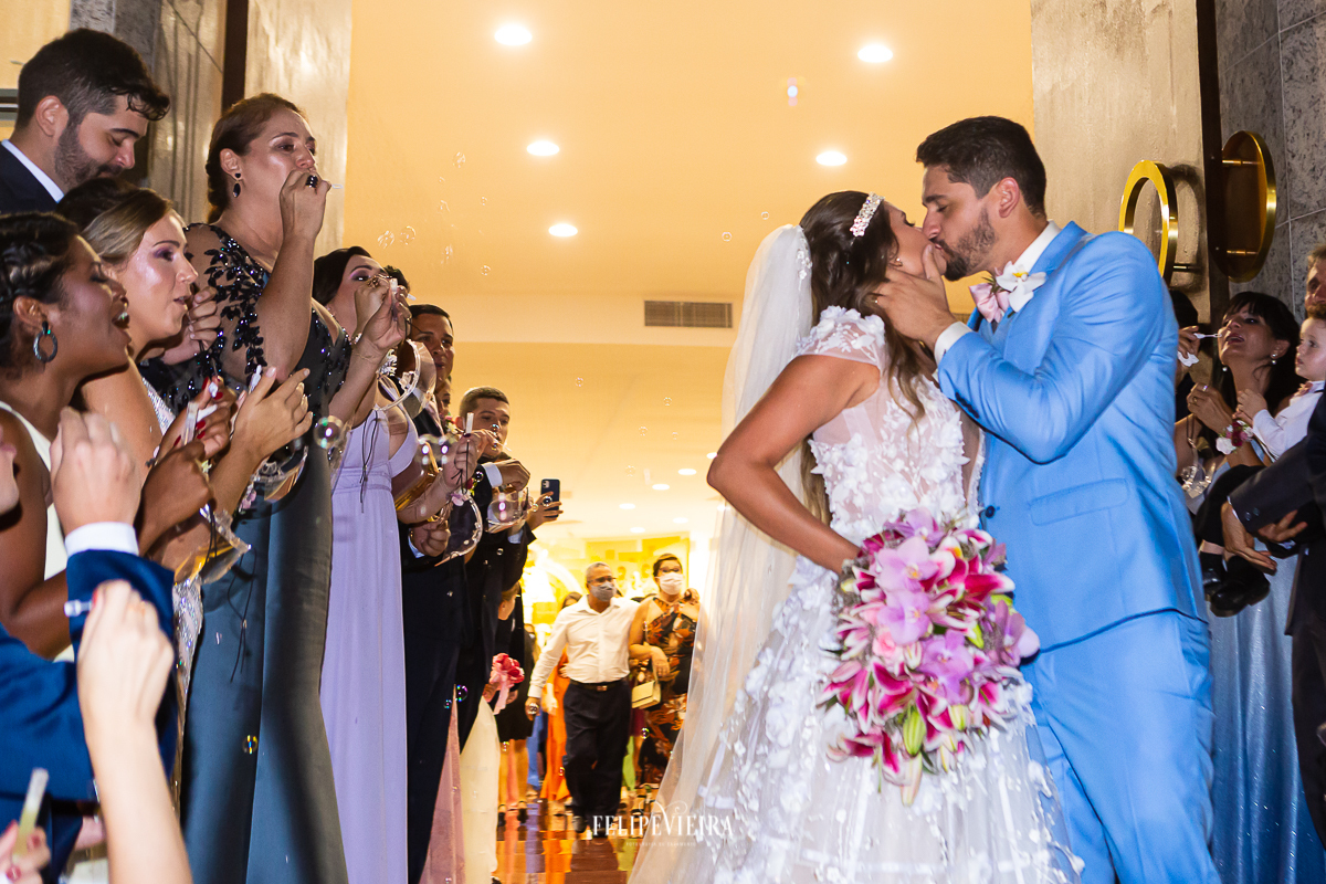 saída dos noivos da igreja se beijando na porta da igreja
