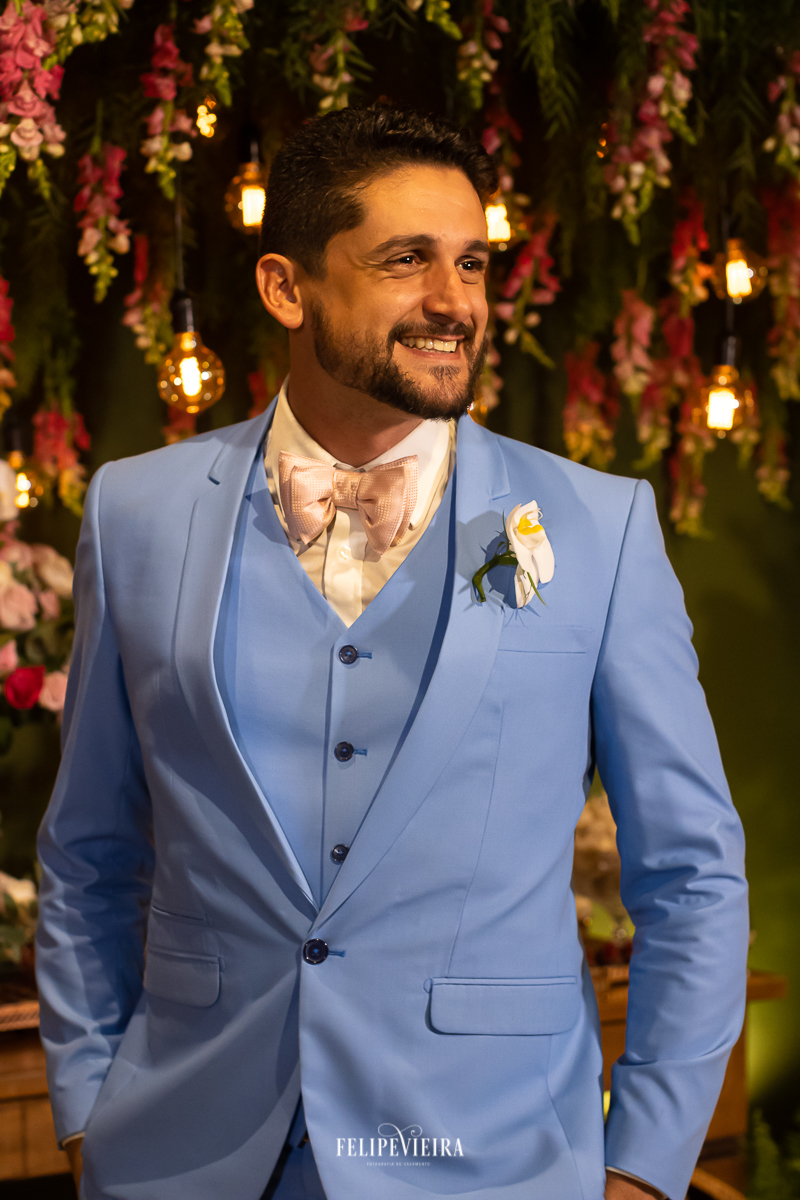 retrato do noivo de terno azul na frente da decoração