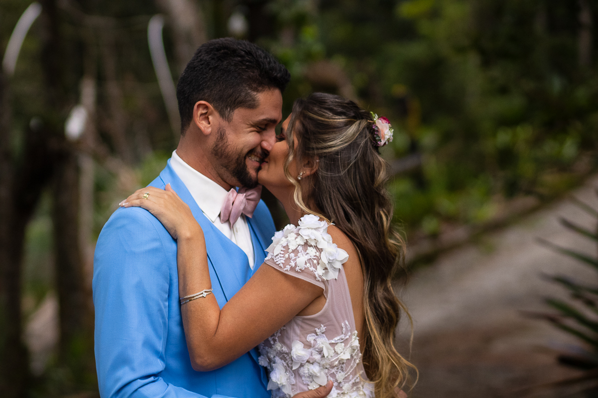 noivos brincando abraçoados e se beijando com o noivo com terno em azul claro gravata rosa 