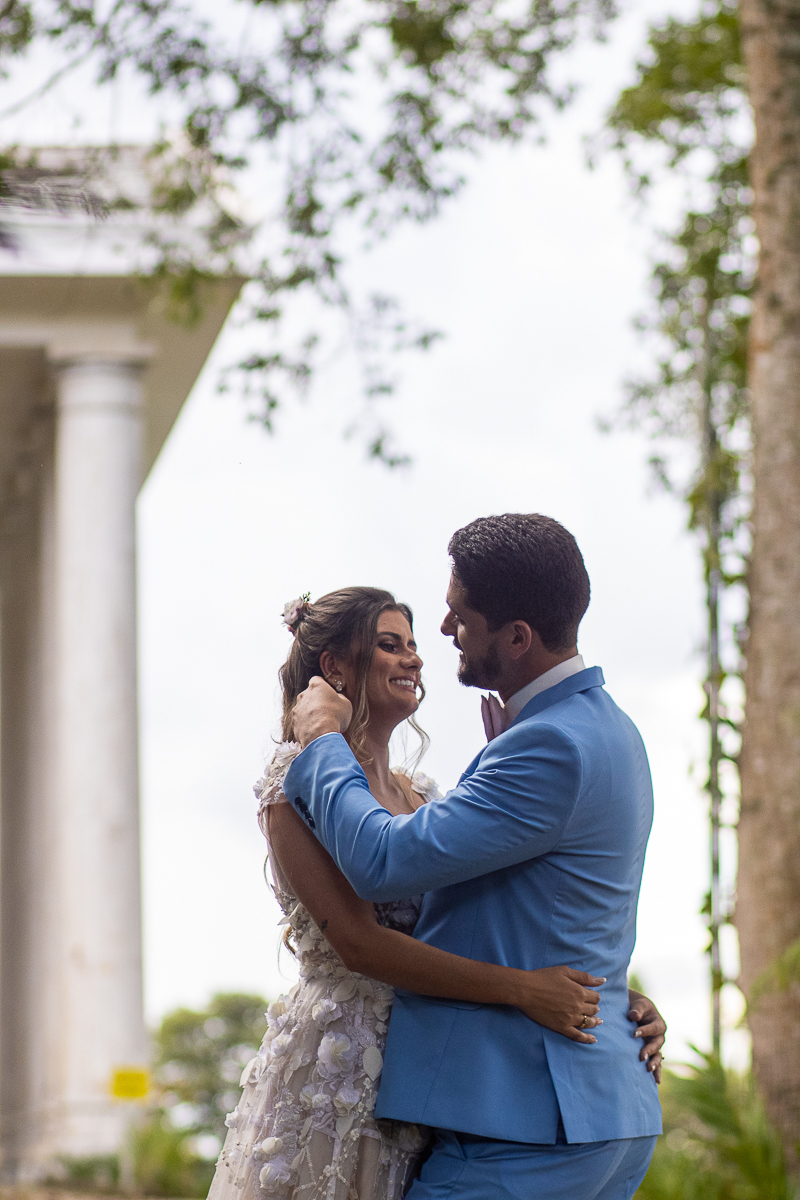 noivos abraçados em área externa com o noivo passando a mão no cabelo da noiva 