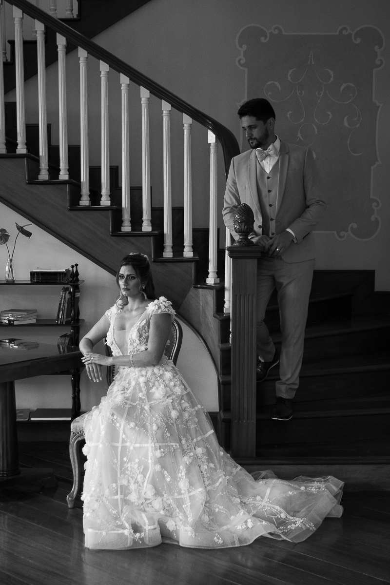 retrato clássico dos noivos com a noiva sentada e o noivo na escada atrás da noiva