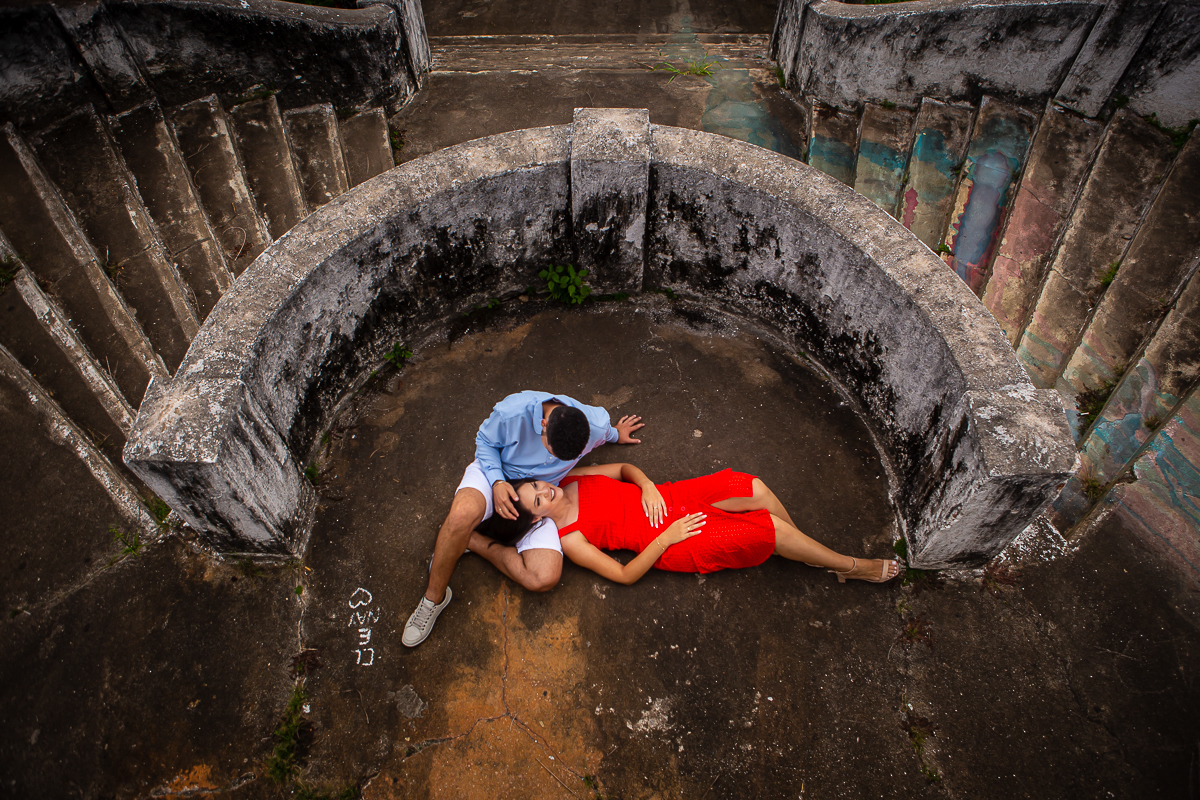 noiva com vestido vermelho na escadaria do santuário em Anchieta deitada no colo do noivo