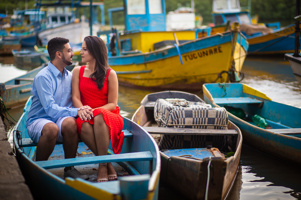 noiva olhando para o noivo dentro do barco com um barco amarelo no fundo