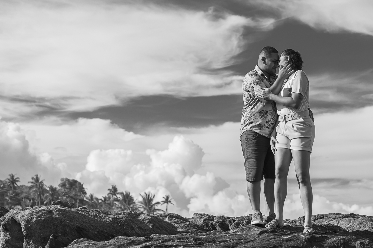 noivos sobre pedras em ensaio pré wedding com o céu no fundo