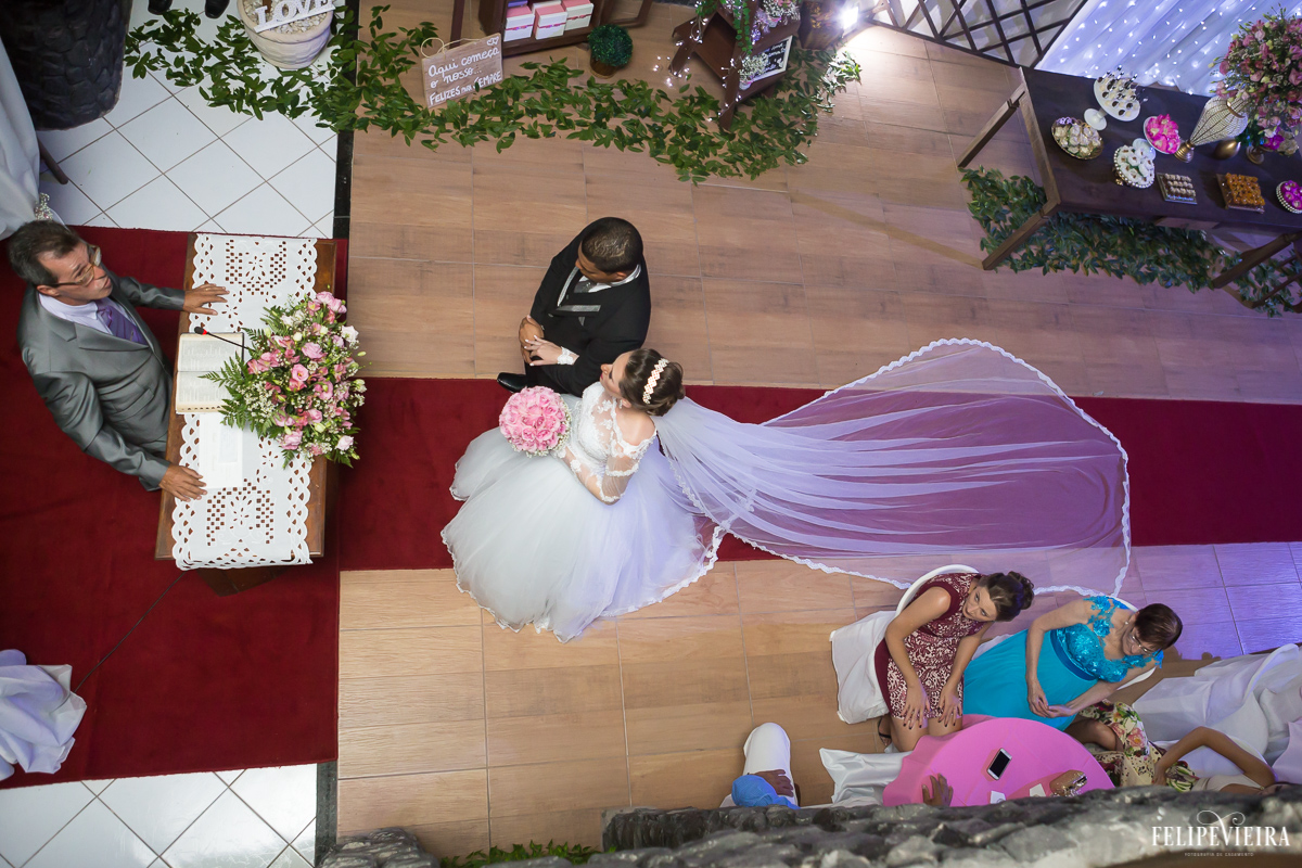 casal noiva com buquê rosa entrando na igreja foto de cima tapete vermelho em guarapari felipe vieira fotografo de casamento fvfotografo