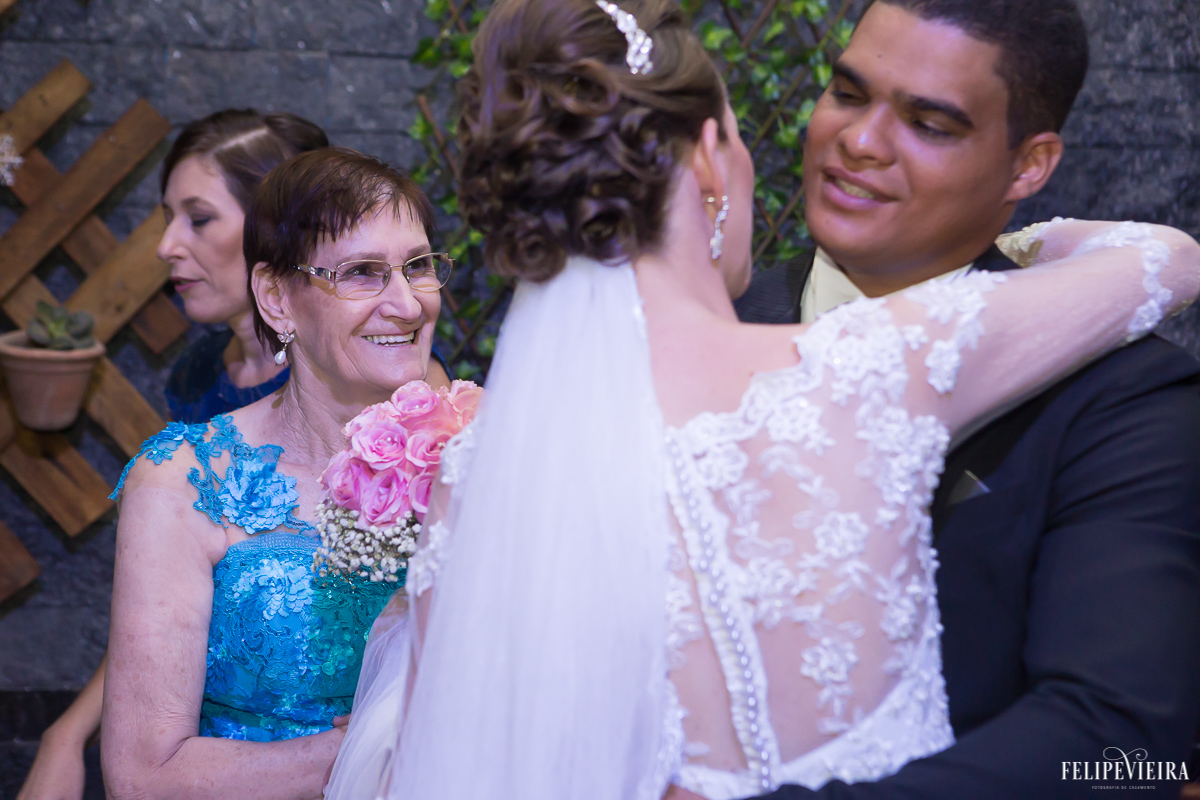 mãe da noiva olhando sua filha no final da cerimonia casal de noivos se abraçando emoção felicidade felipe vieira fotografo de casamento guarapari