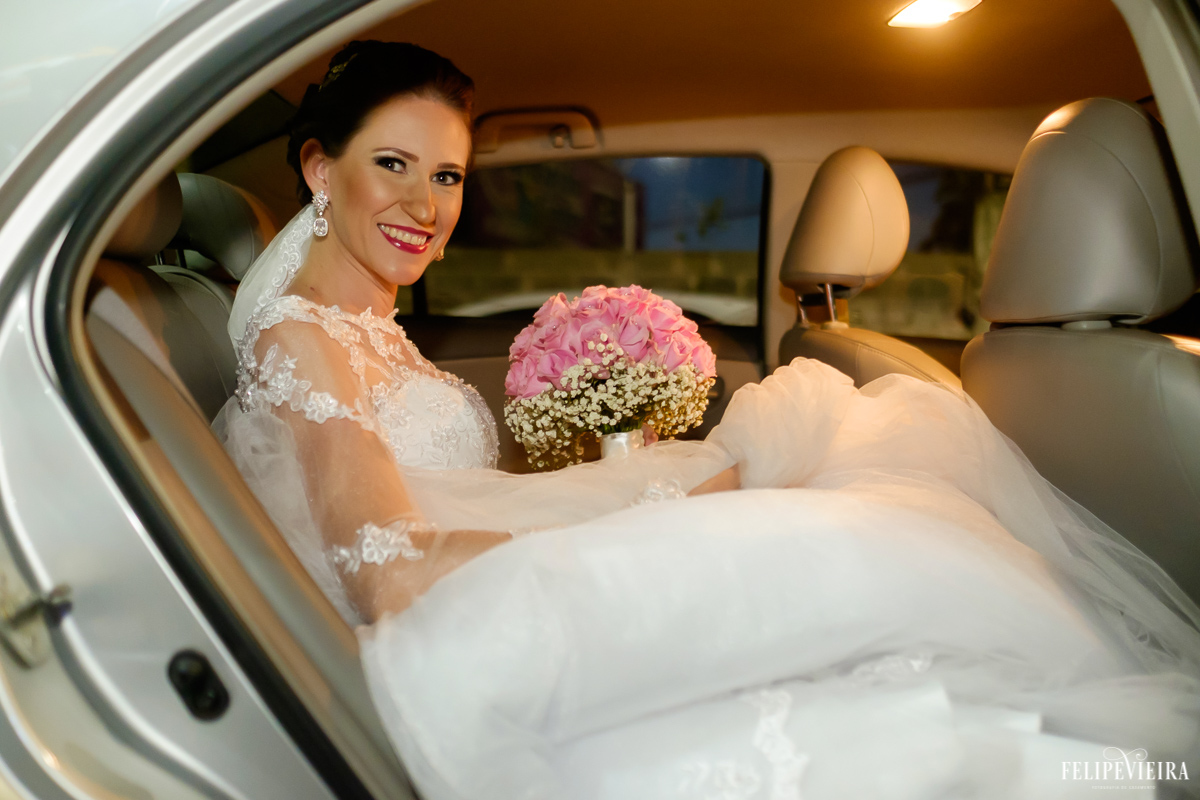 noiva sorrindo no carro com buquê rosa em guarapari felipe vieira fotografo de casamento fvfotografo