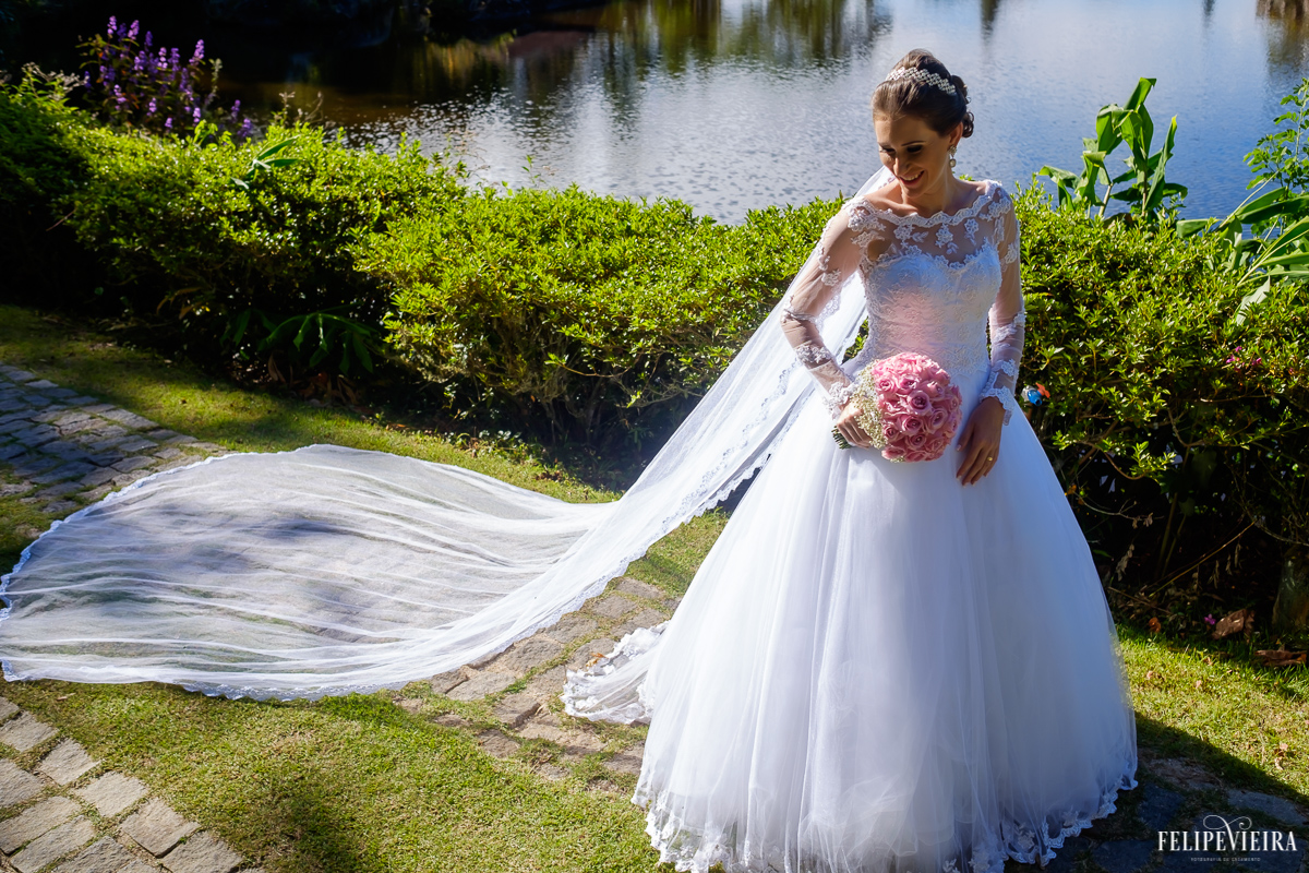noiva com buquê rosa felipe vieira fotografo na pousada pedra azul lago ao fundo véu esticado vestido branco fotografo de guarapari