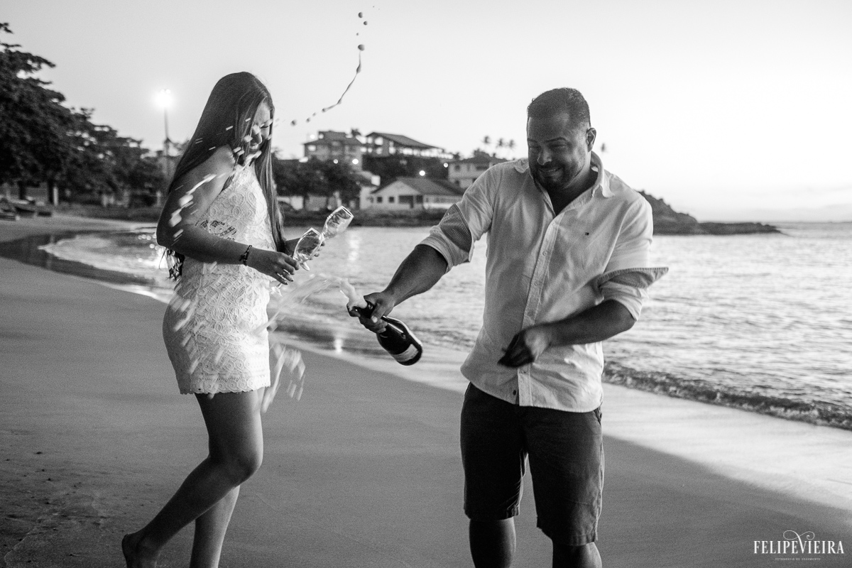 Brincadeira da Nana e do Edy estourando o champagne durante o ensaio pre wedding feito na praia de Meaípe pelo fotografo Felipe Vieira em Guarapari