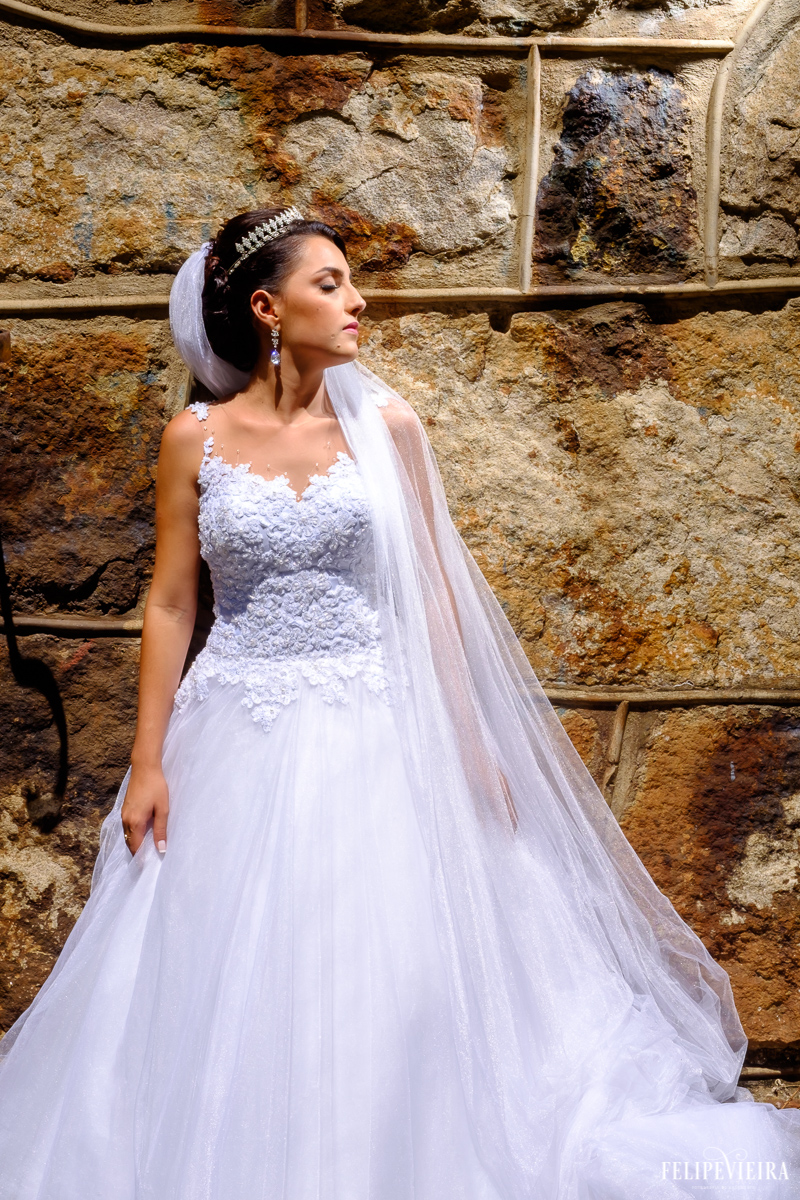 noiva em frente a um paredão com o véu caindo sobre um ombro foto feita por felipe vieira fotógrafo de casamentos guarapari