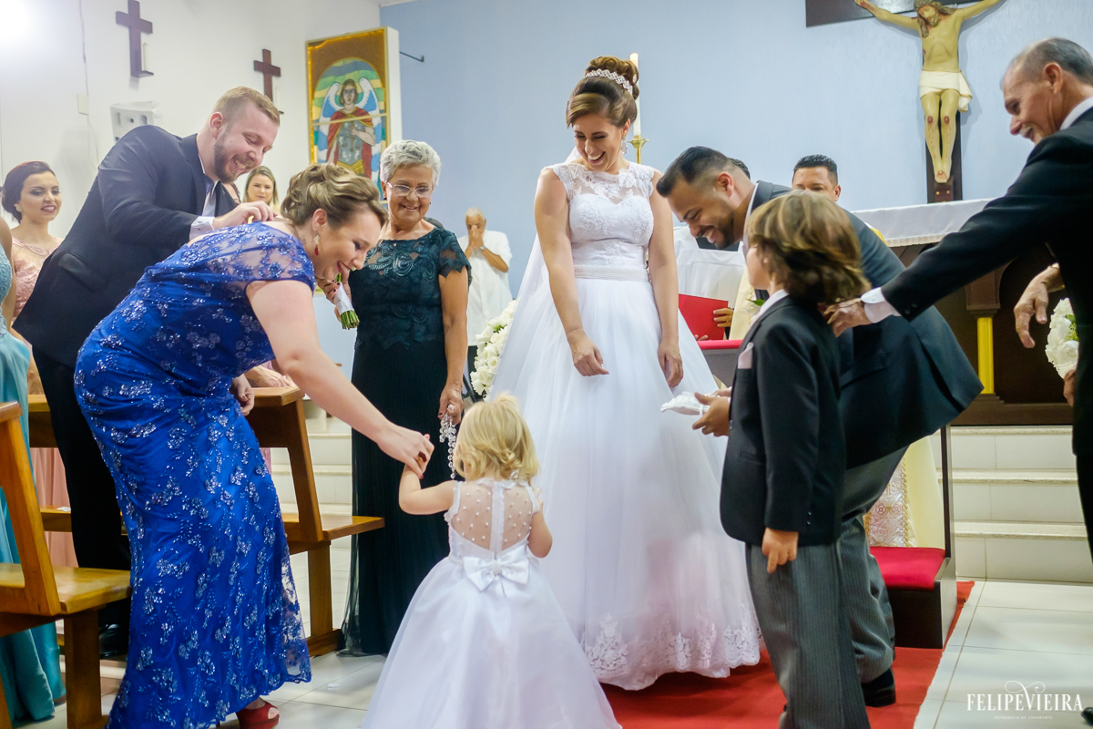 noivos e convidados se divertindo com a noivinha levando as alianças durante cerimonia de casamento felipe vieira fotografia de casamento em guarapari espirito santo