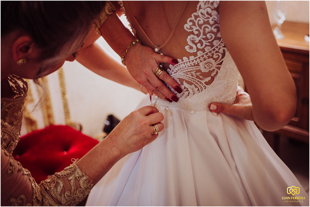 mãe fechando o vestido da filha que vai se casar 