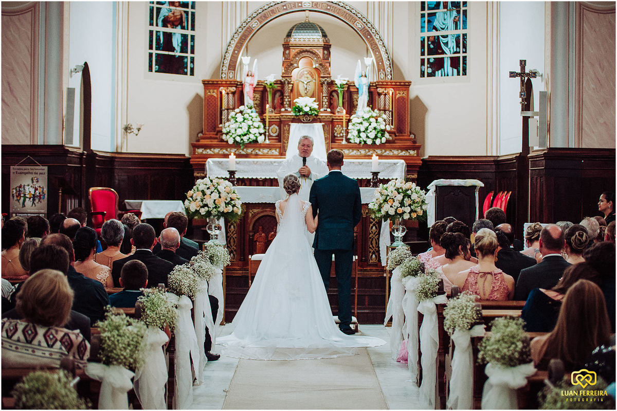 noivos na frente do alta, com o padre lendo a palavra