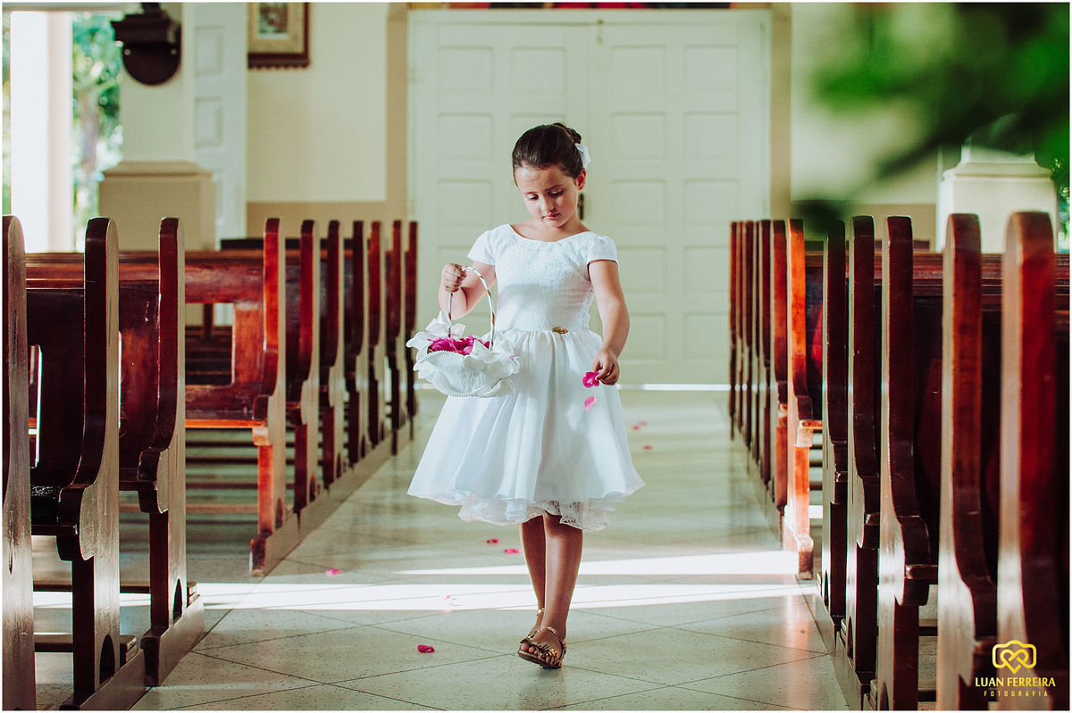 noivinha entrando na igreja jogando pétalas de rosas no corredor do igreja  