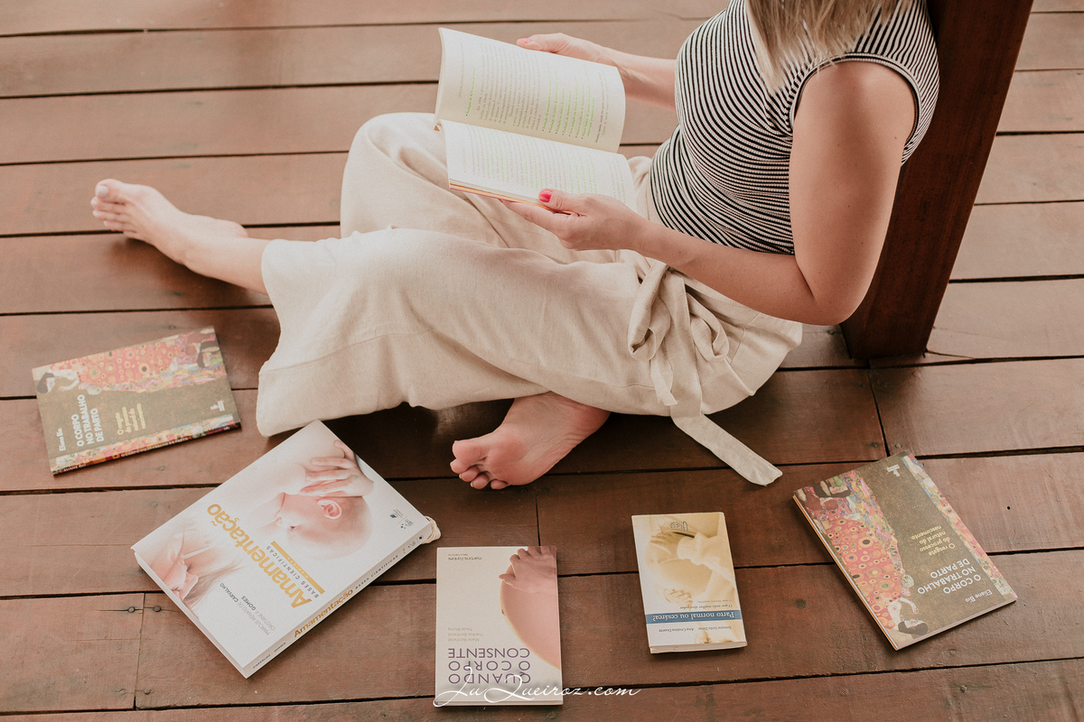 mulher lendo livros sobre parto normal, doula, amamentação.