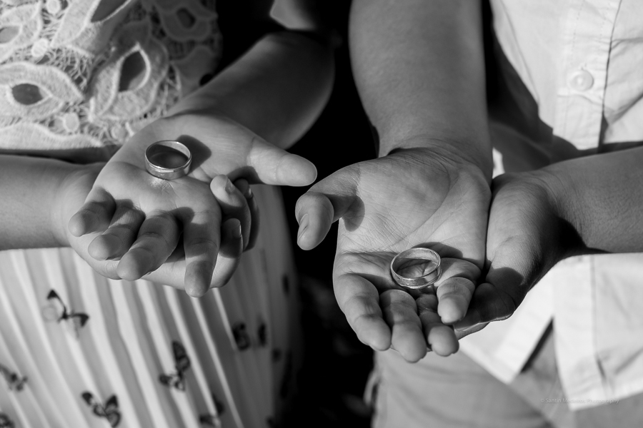 en esa foto se ve las manos de dos niños pequeños sujetando los anillos de boda de sus padres
