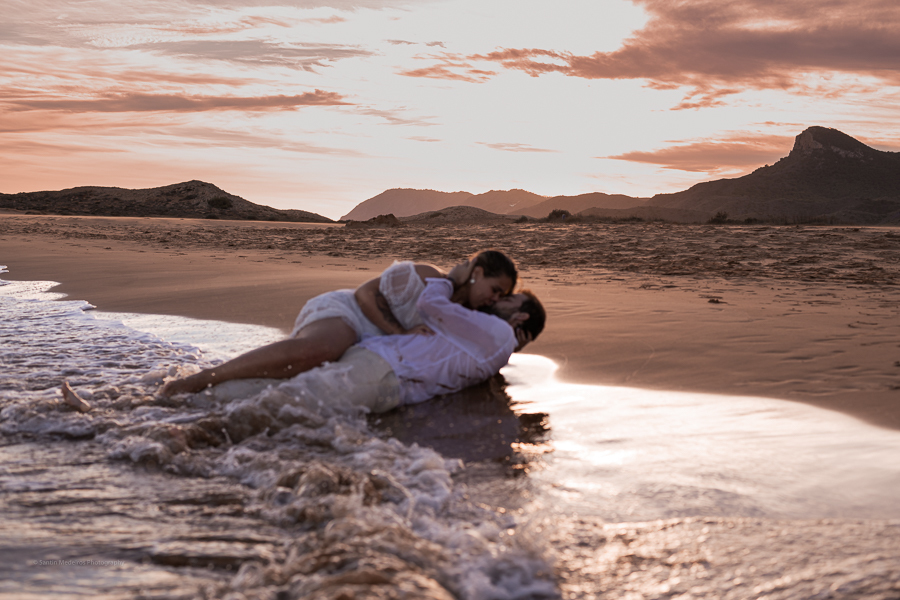 novios tumbados en la orilla del mar