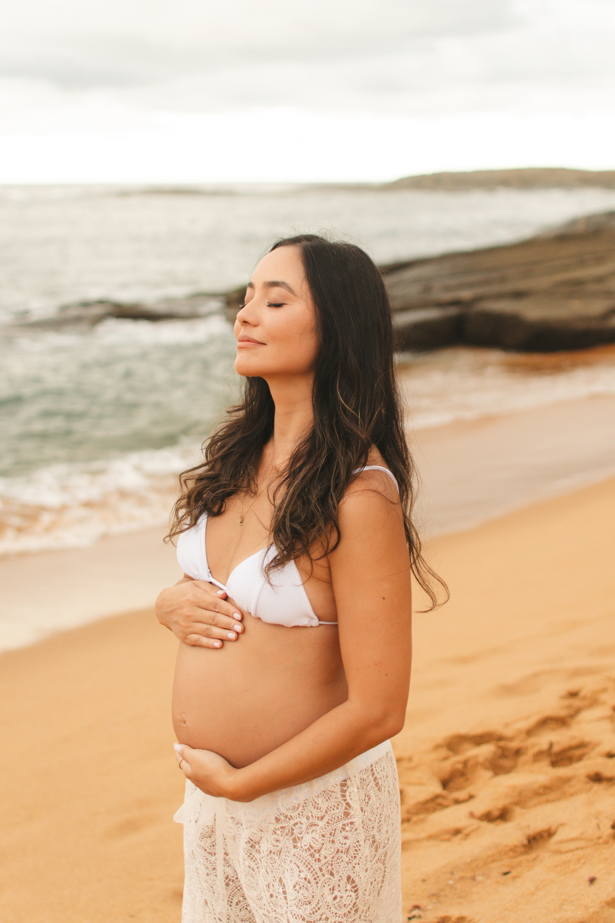 Mamãe acariciando a barriga com ternura, em um ensaio de gestação cheio de emoção e esperança.