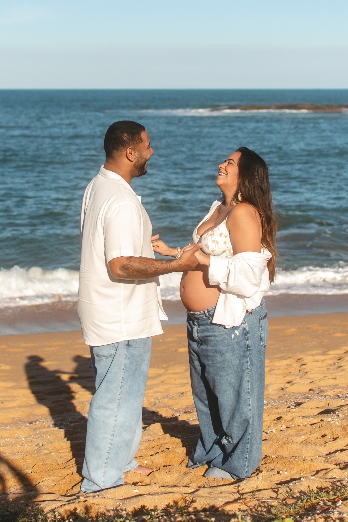 Casal sorrindo e conversando durante ensaio na praia em Guarapari.