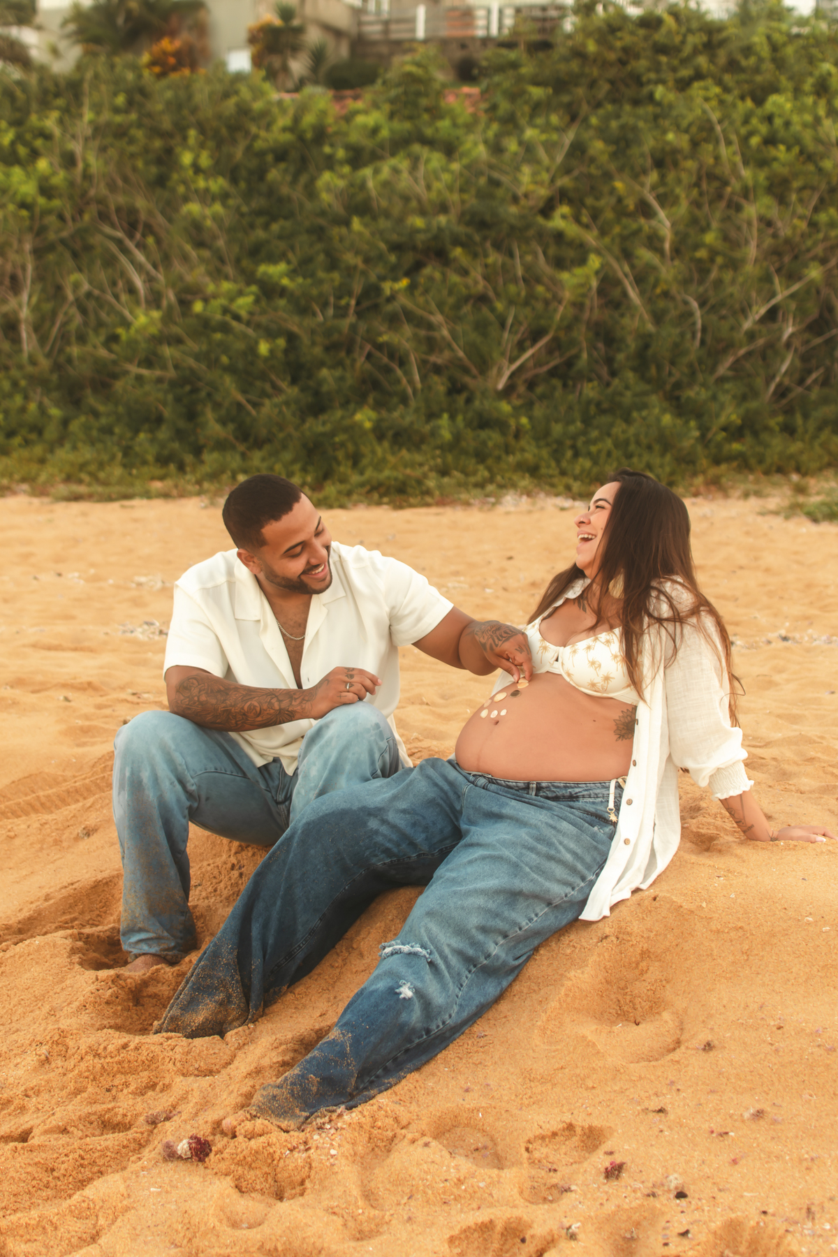 Casal sorrindo e brincando durante ensaio de gestante.