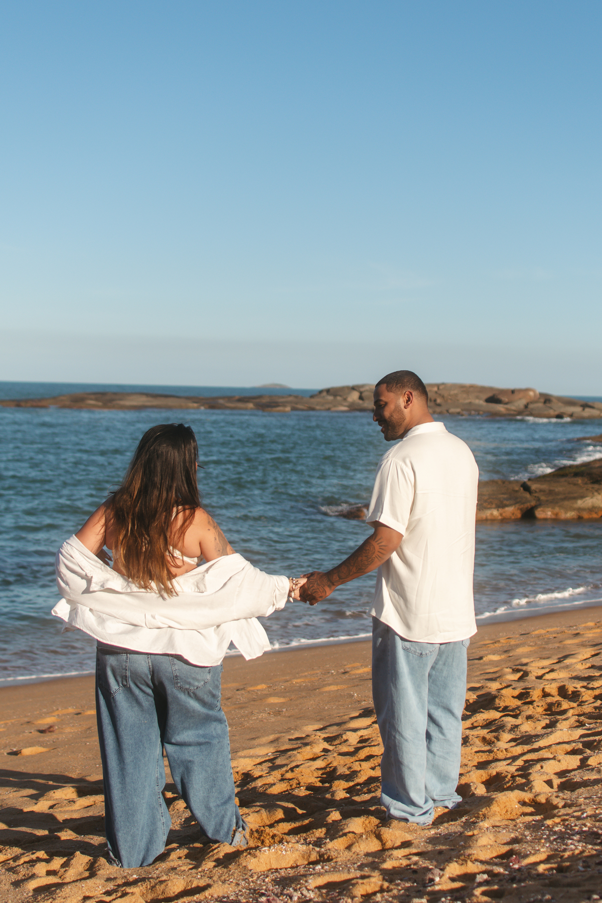 Casal apreciando o pôr do sol durante ensaio de gestante em Guarapari ES.