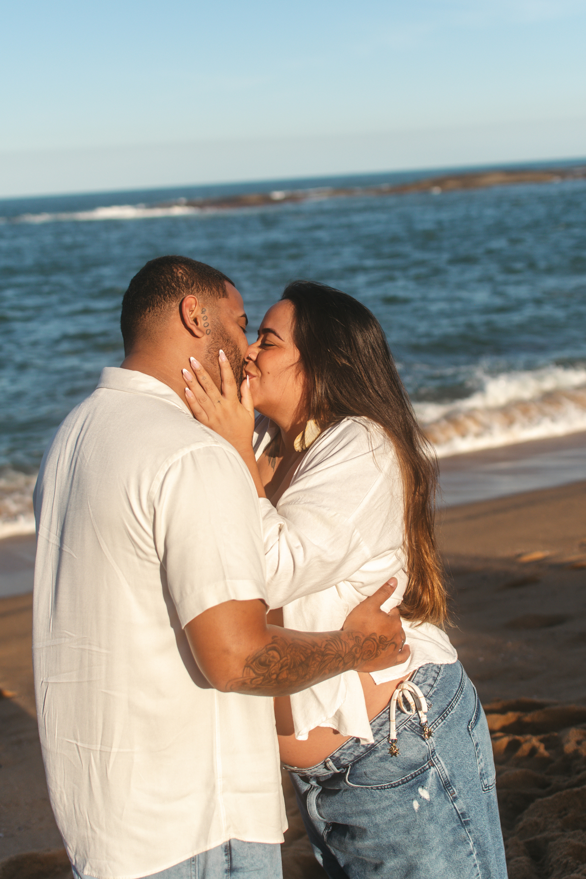 Casal trocando beijos em ensaio fotográfico na praia em Guarapari.