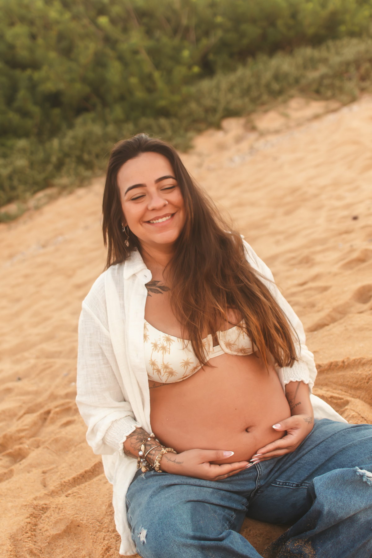 Gestante sorrindo sentada na praia em Guarapari.
