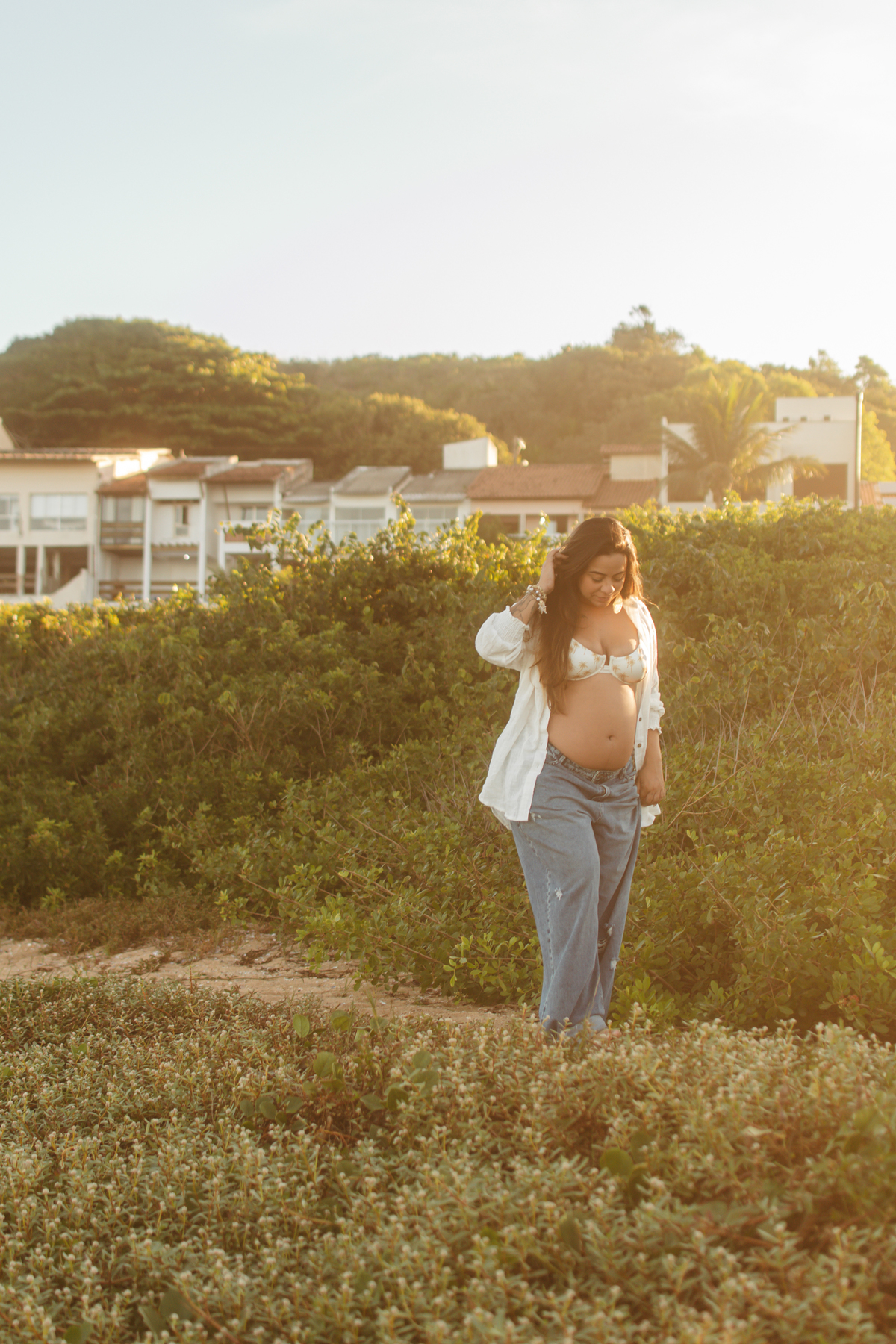Gestante caminhando ao pôr do sol durante ensaio em Guarapari.