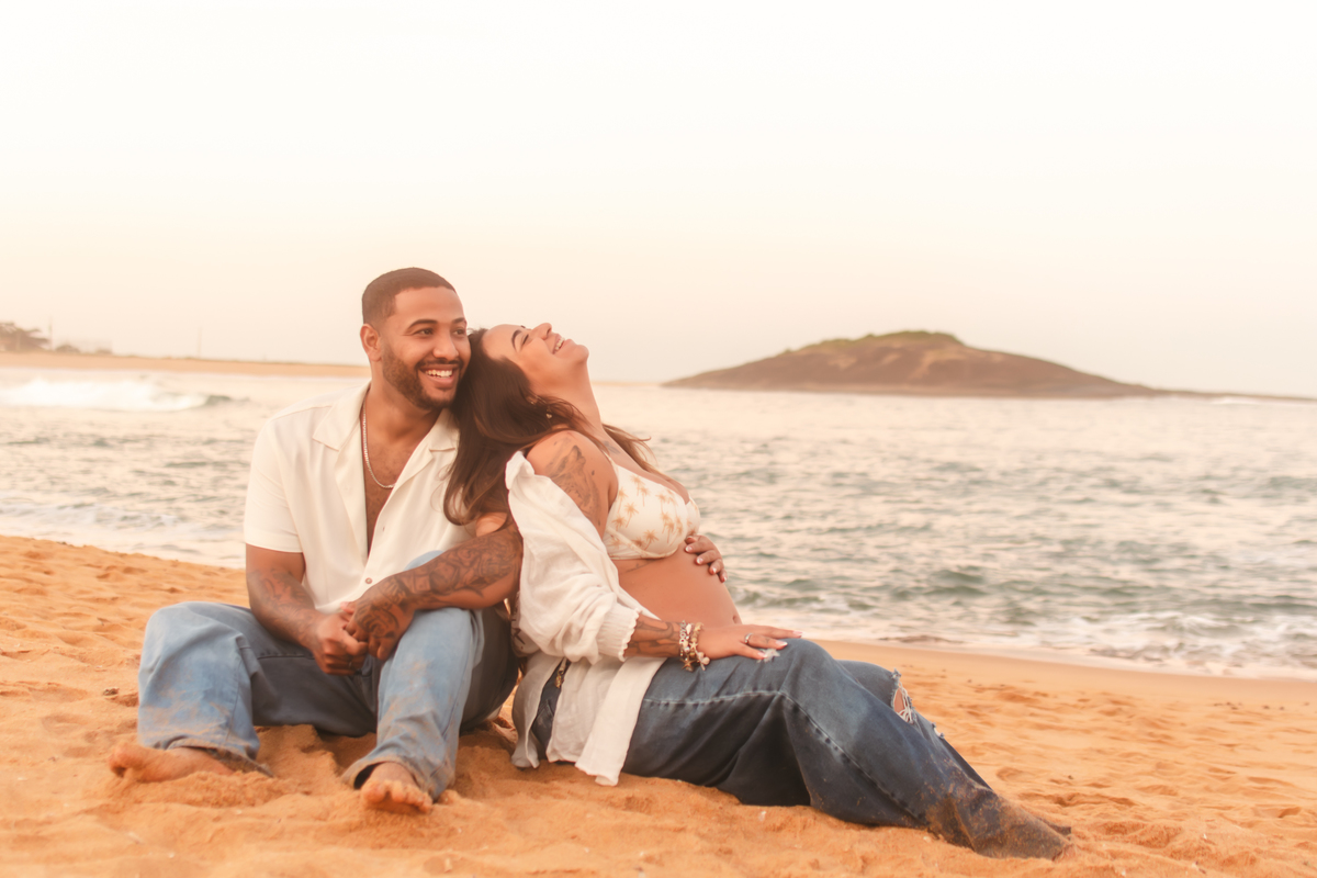 Casal sentados na areia conversando e rindo em ensaio em Guarapari/ES.