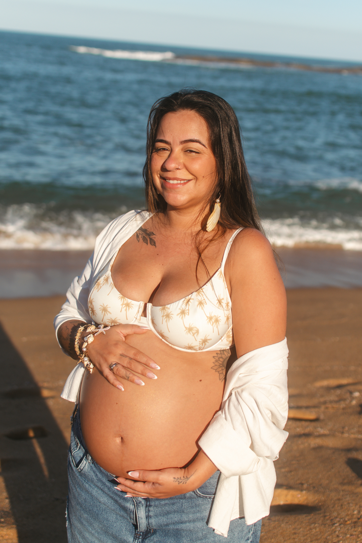 Grávida sorrindo durante ensaio ao pôr do sol.