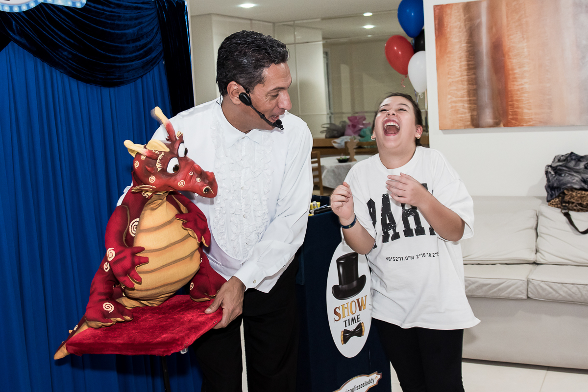 mágico com dragão vermelho e menina gargalhando