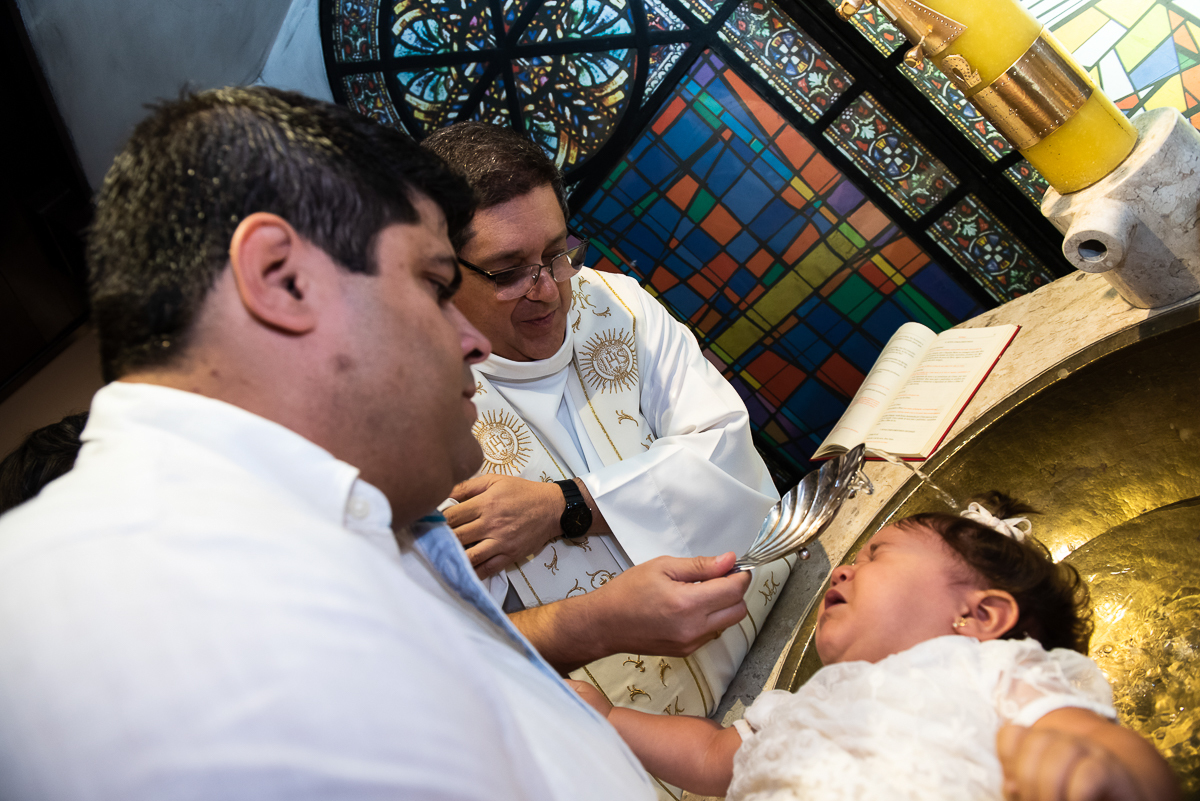 molhando a cabeça da criança com água benta