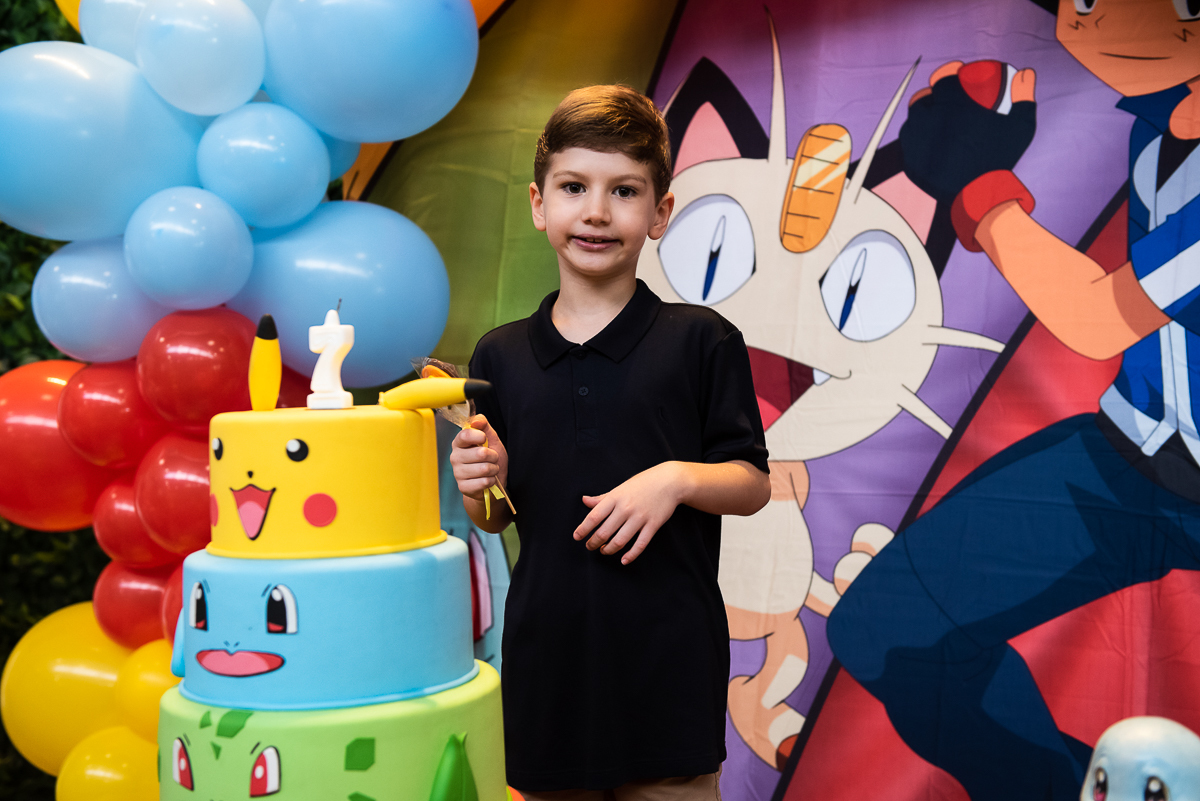 menino de camiseta preta perto do bolo de parabéns
