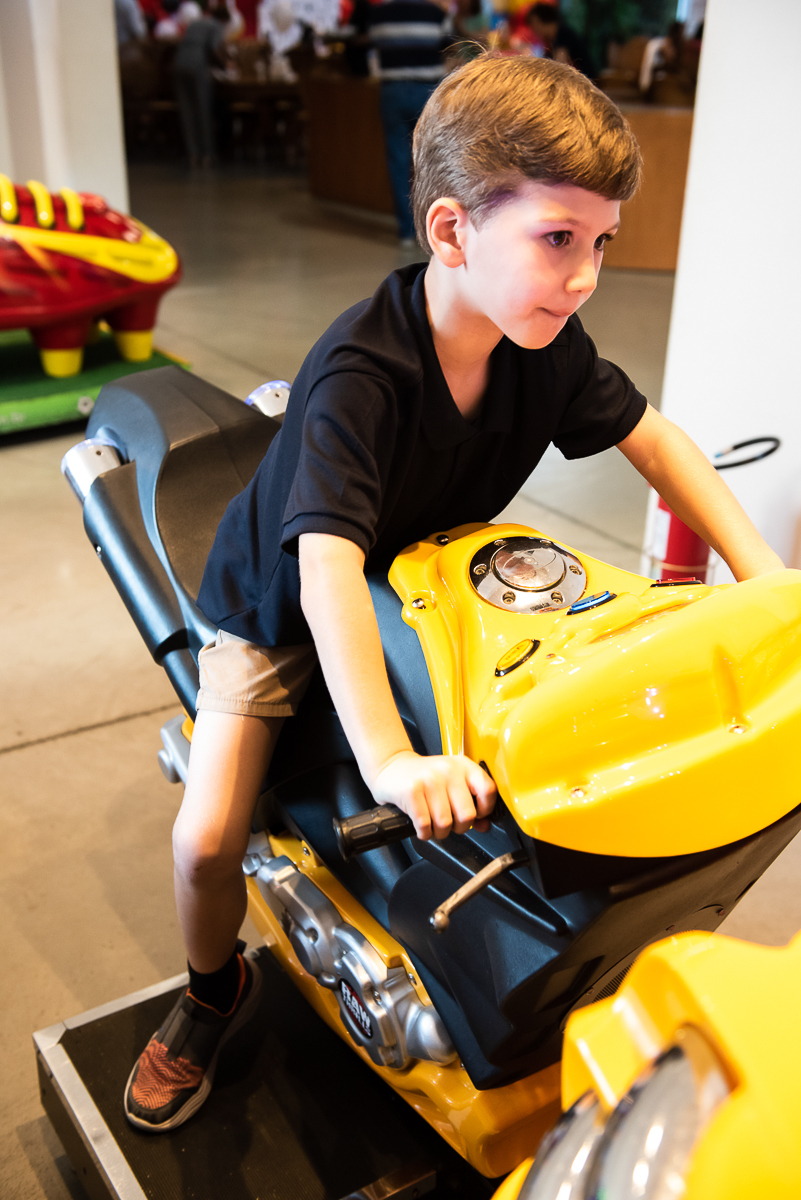 criança se divertindo na moto de brinquedo, amarela e preta