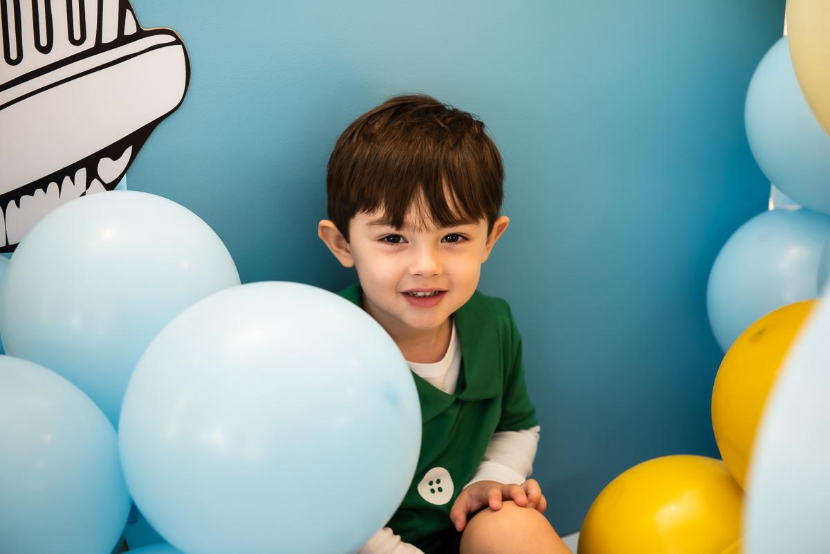 menino de blusa verde e balões azul e amarelo