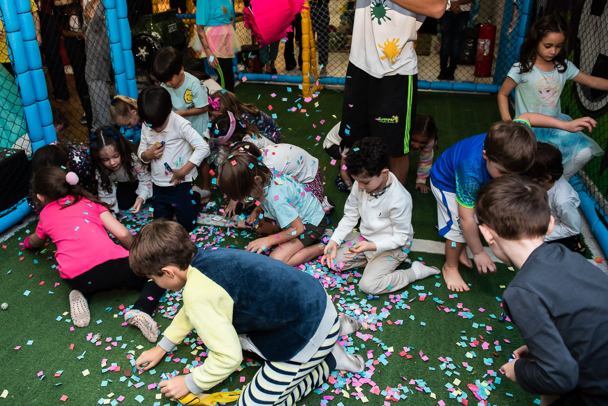 as crianças pegando os doces que caíram no chão