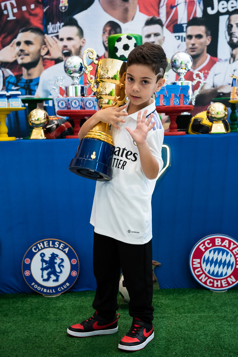 menino abraçando o troféu de campeão de futebol