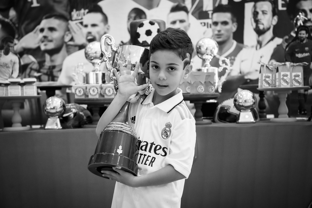criança com o troféu de campeão na mão, fotografia em preto e branco