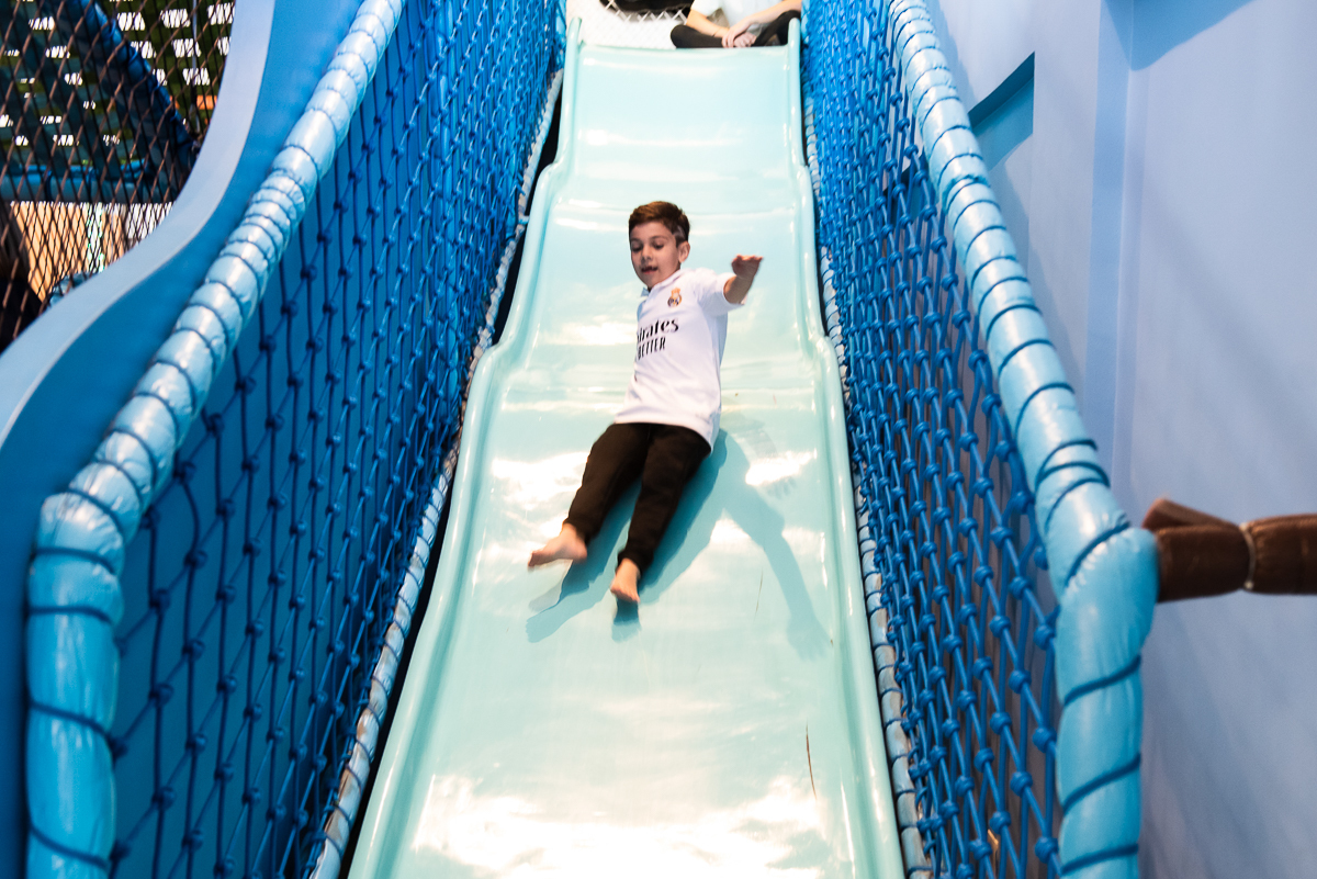 menino descendo o escorregador azul