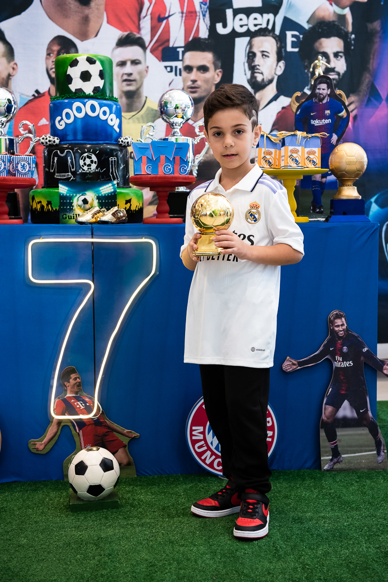 Menino segurando a taça de futebol