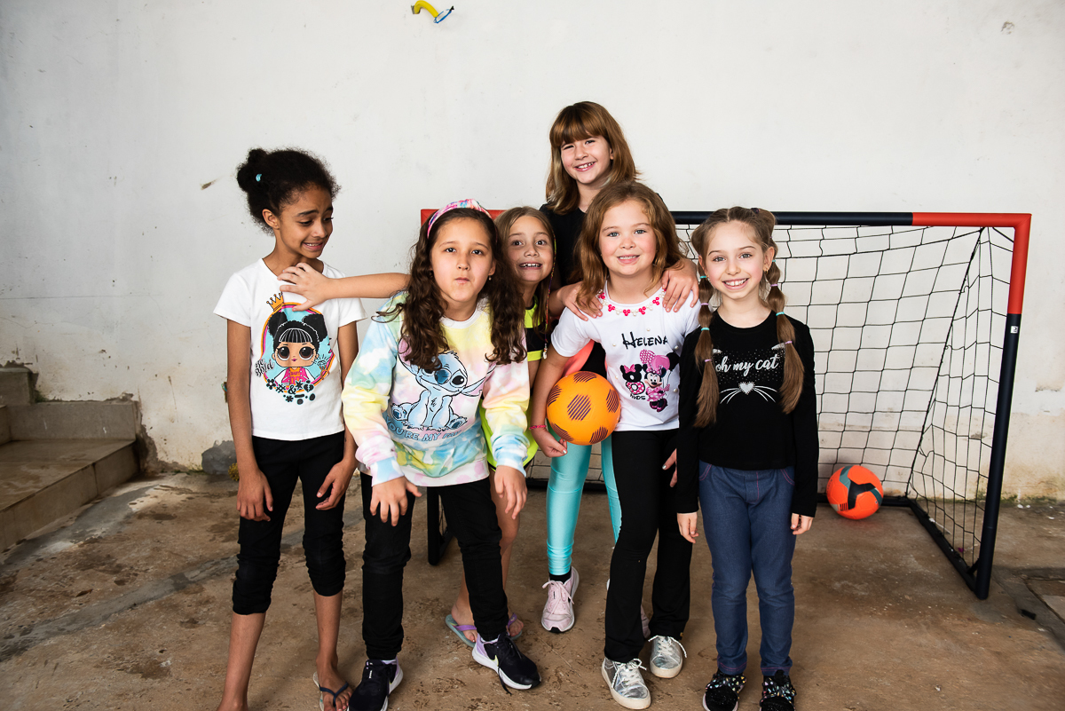 várias meninas tirando foto perto da trave do gol