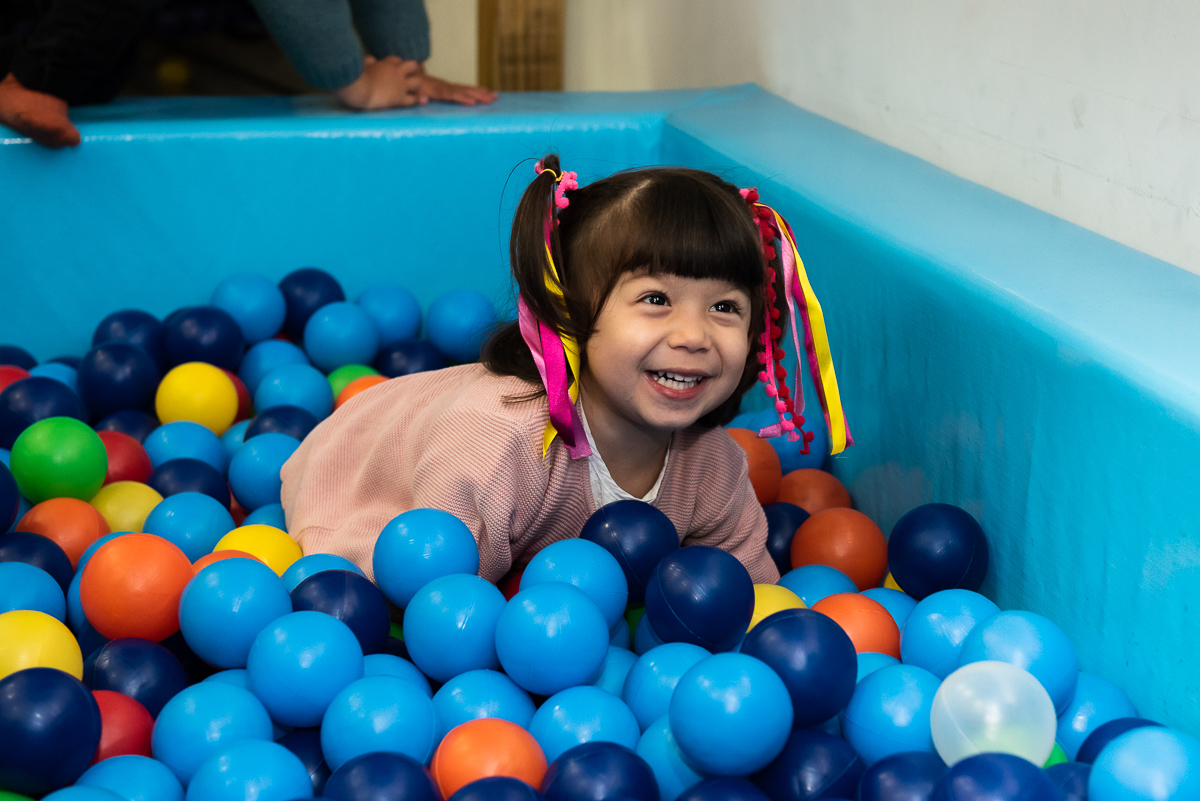 menininha sorridente curtindo a piscina de bolinha