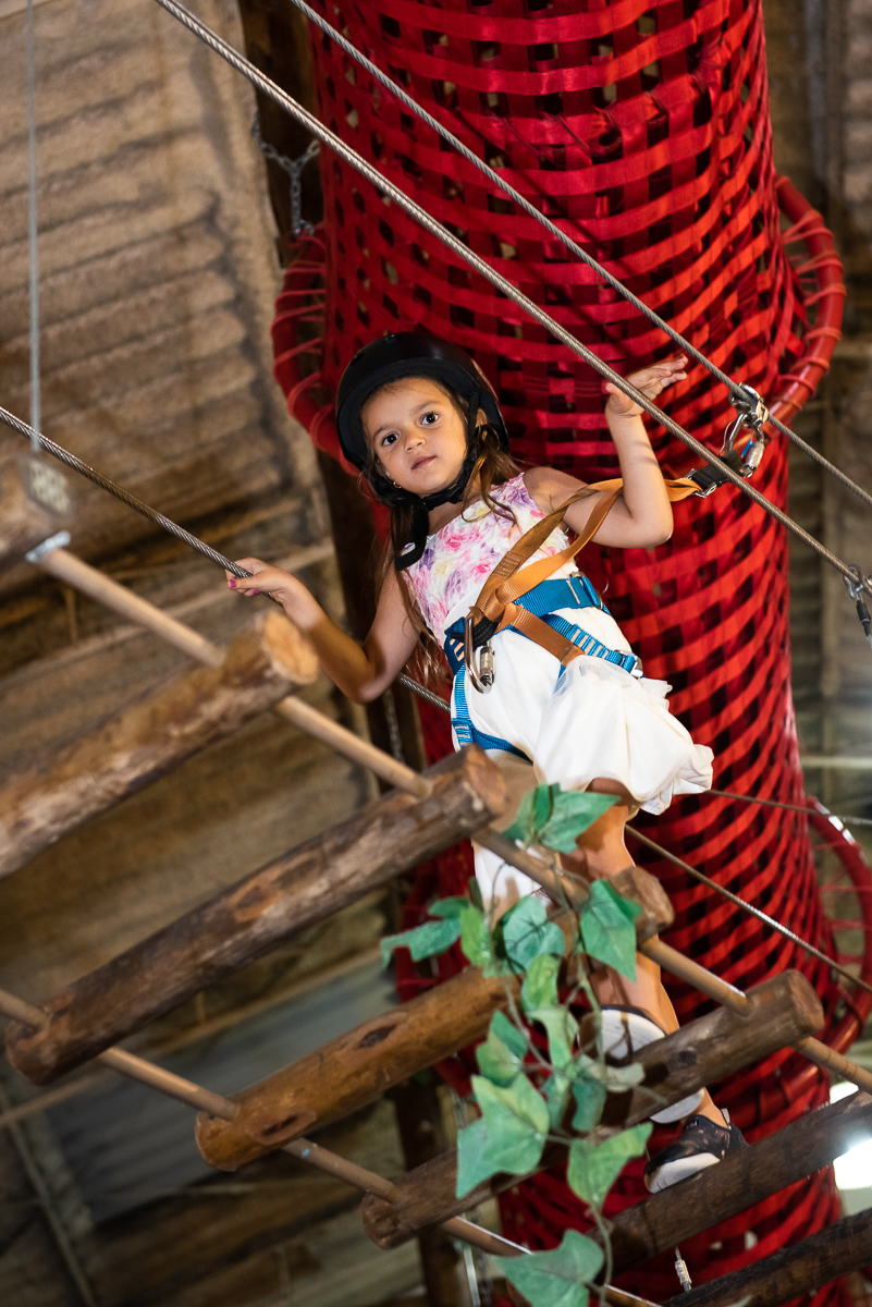 linda menina curtindo a escada suspensa do brinquedão do buffet Espaço Puzzle